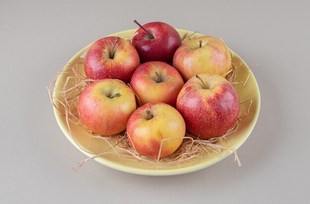 Deliciosas manzanas y paja en un cuenco de mármol