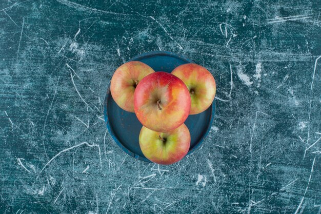 Deliciosas manzanas en una placa de madera, sobre la mesa de mármol.