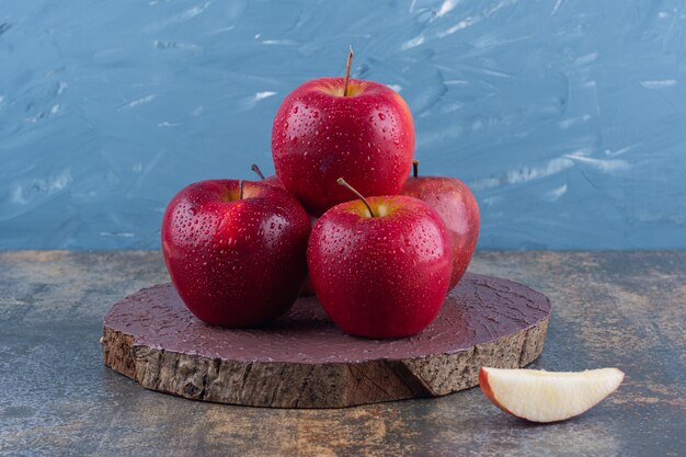 Deliciosas manzanas rojas brillantes colocadas sobre tabla de madera.