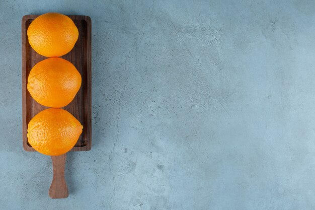 Deliciosas naranjas sobre una tabla, sobre la mesa de mármol.