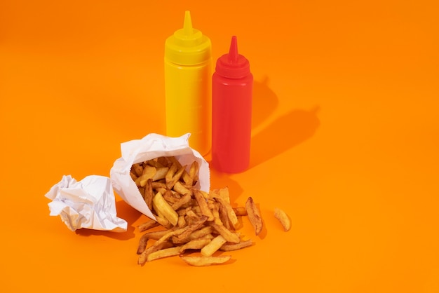 Deliciosas papas fritas de alto ángulo con botellas de salsa