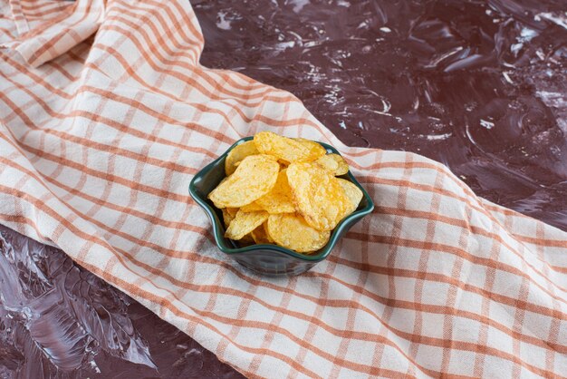 Deliciosas papas fritas en un cuenco sobre un paño de cocina, sobre la mesa de mármol.