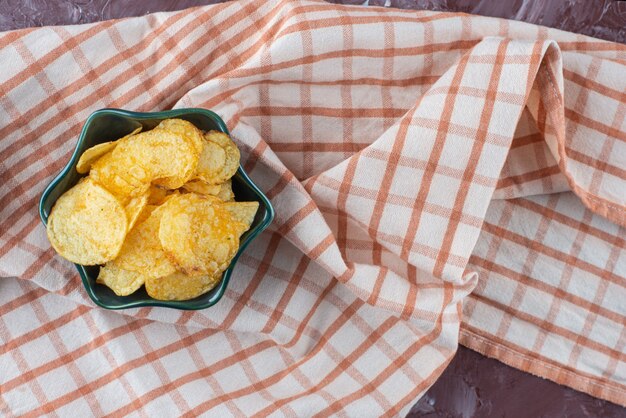 Deliciosas papas fritas en un cuenco sobre un paño de cocina, sobre la mesa de mármol.