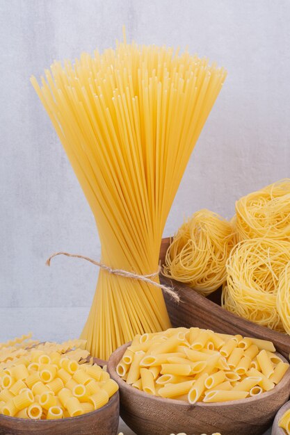 Deliciosas pastas crudas y macarrones en cuencos de madera.