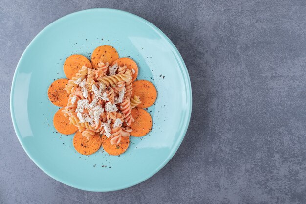 Deliciosas pastas fusilli y zanahoria en placa azul.