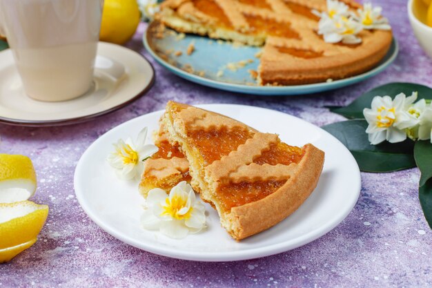 Deliciosas rodajas de tarta de limón con limones frescos y una taza de té, vista superior