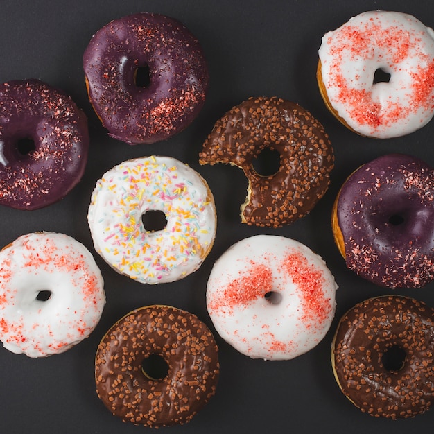 Foto gratuita deliciosas rosquillas mordidas diferentes con glaseado sobre fondo negro