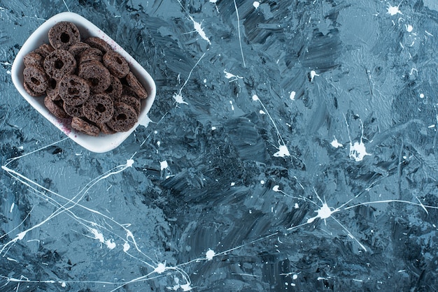 Foto gratuita delicioso aro de maíz bañado en chocolate en un cuenco, sobre la mesa de mármol.