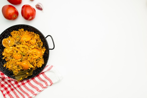 Delicioso arroz español en una paellera sobre fondo blanco.