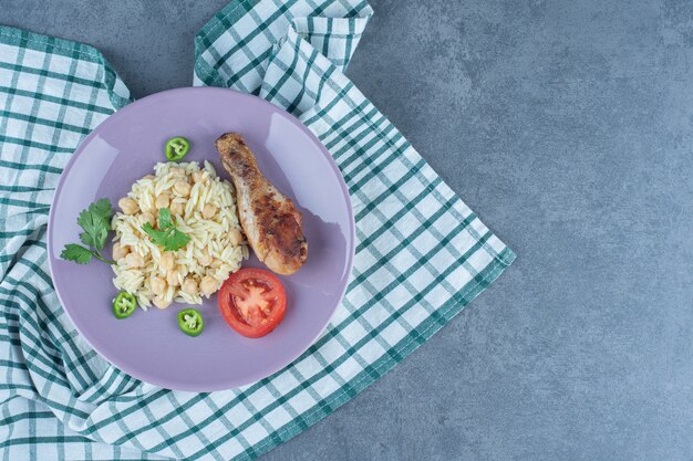 Delicioso arroz con garbanzos y muslo en plato morado.