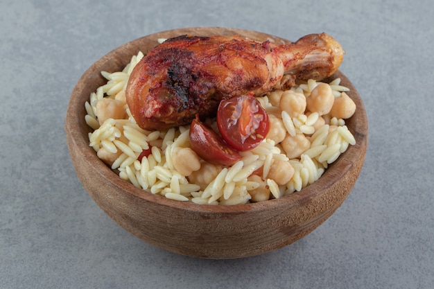 Delicioso arroz con garbanzos y pollo muslo de pollo en un tazón de madera.