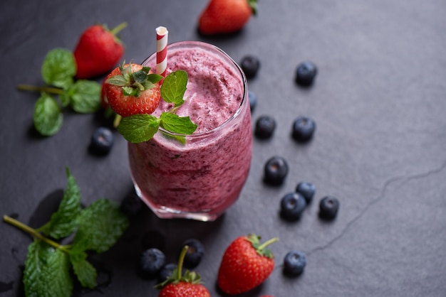 Delicioso batido de fresa, mora y arándano aderezado con fresas frescas y menta en vaso. enfoque suave. hermoso aperitivo frambuesas rosas, bienestar y concepto de pérdida de peso.