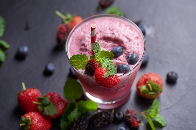 Delicioso batido de fresa, mora y arándano aderezado con fresas frescas y menta en vaso. enfoque suave. hermoso aperitivo frambuesas rosas, bienestar y concepto de pérdida de peso.