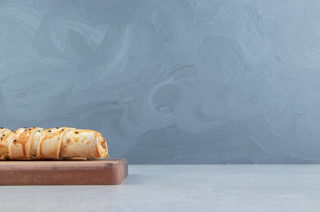 Delicioso bollo trenzado sobre tabla de madera.