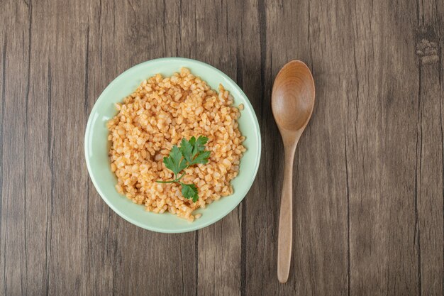 Delicioso bulgur con verduras en placa verde con cuchara.