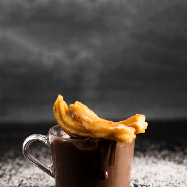 Delicioso chocolate derretido en una taza con churros