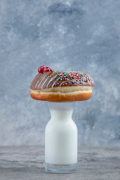 Un delicioso chocolate espolvorea una rosquilla sobre un vaso de leche.