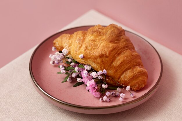 Delicioso croissant de alto ángulo con flores.