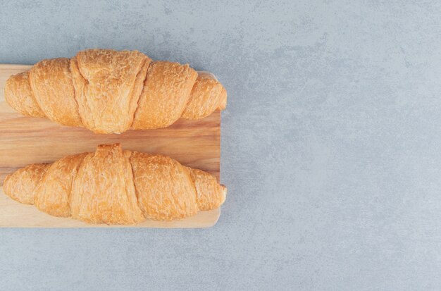 Delicioso croissant en el tablero, sobre el fondo de mármol. Foto de tablero de alta calidad