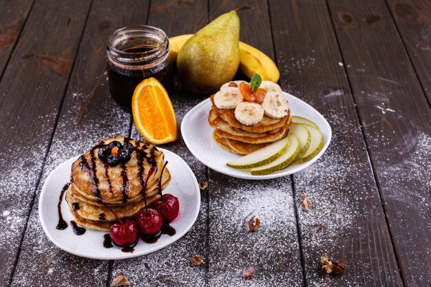 Delicioso desayuno Deliciosos panqueques cubiertos de chocolate, cerezas, plátanos y peras