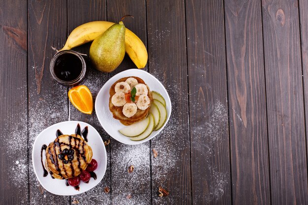 Delicioso desayuno Deliciosos panqueques cubiertos de chocolate, cerezas, plátanos y peras