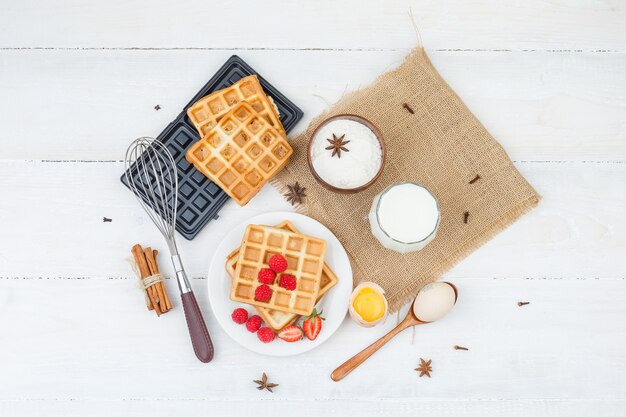 Delicioso desayuno con gofres, leche y frutos rojos.