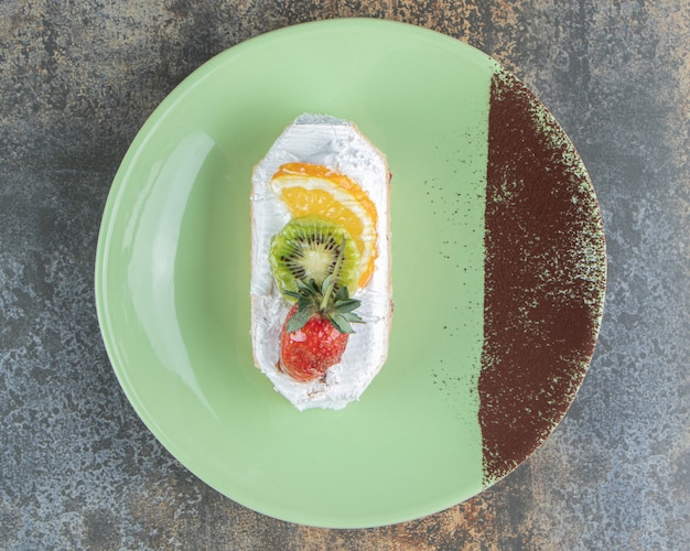 Un delicioso eclair con frutas en una placa verde