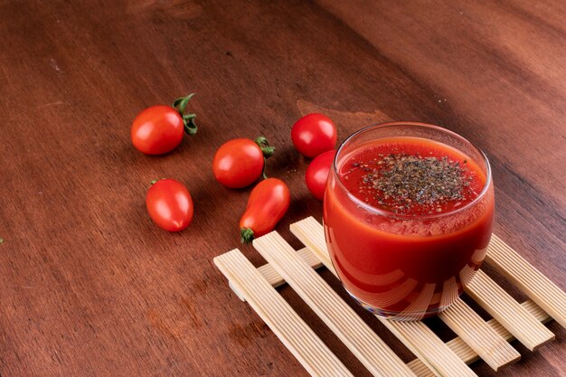 delicioso jugo de tomate rojo en vaso con pimienta negra en la mesa de madera