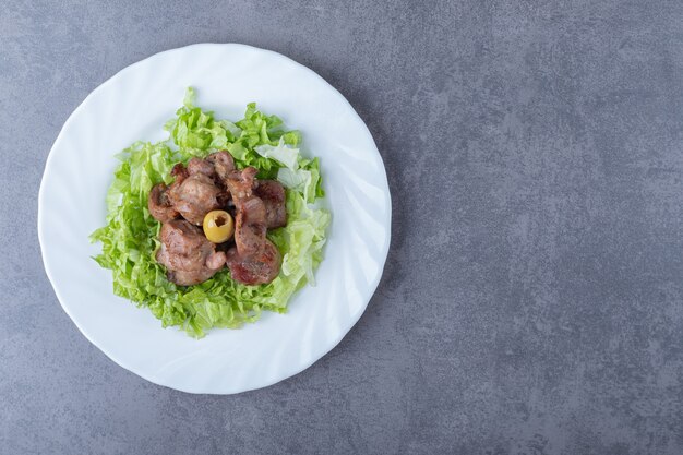 Delicioso kebab de hígado con lechuga en un plato blanco.