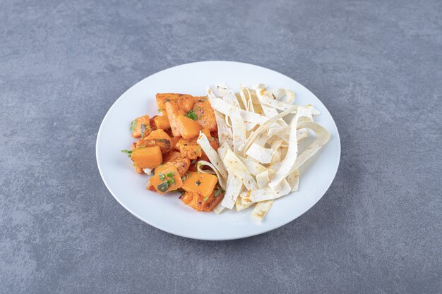 Delicioso lavash en rodajas y zanahoria al horno en plato, sobre la superficie de mármol.