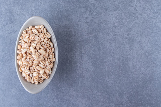 Delicioso muesli en un cuenco, sobre la mesa azul.