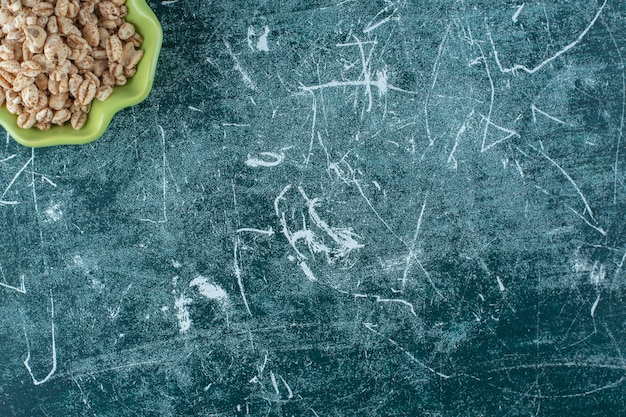 Delicioso muesli en un cuenco, sobre la mesa azul.