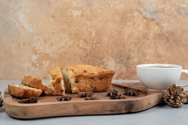 Delicioso muffin con pasas y taza de té sobre tabla de madera.