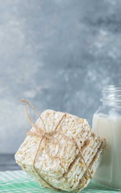 Delicioso pan crujiente cuadrado y botella de leche sobre mármol.