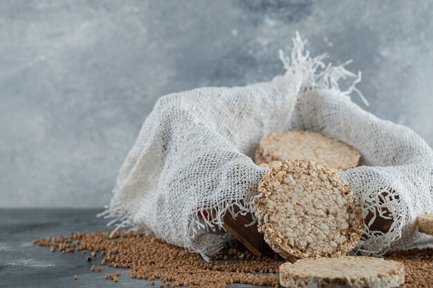 Delicioso pan crujiente y trigo sarraceno crudo sobre superficie de mármol