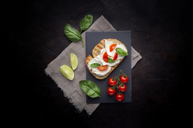 Delicioso pan con queso y tomate sobre un fondo negro