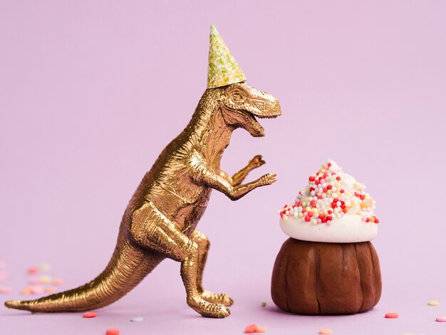 Delicioso panecillo y dinosaurio con gorro de cumpleaños