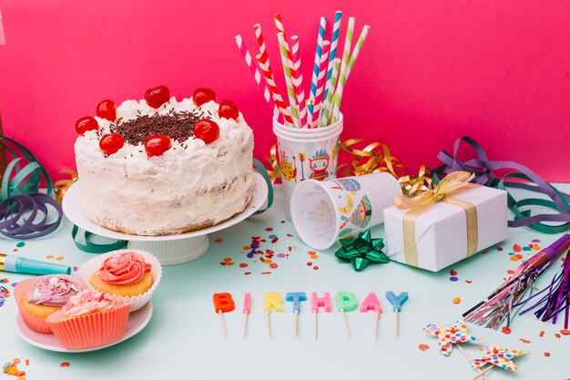 Delicioso pastel blanco con accesorios de fiesta en doble fondo.