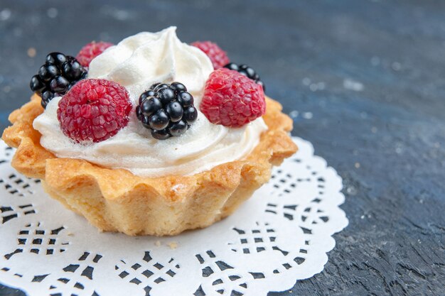 delicioso pastel dulce con bayas y crema sobre gris oscuro