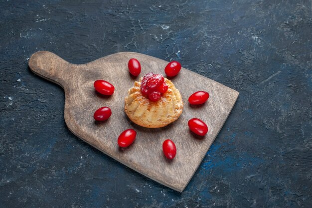 delicioso pastel dulce con cornejos rojos sobre gris oscuro, galleta de pastel de frutas y bayas