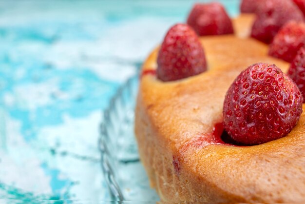 Delicioso pastel de fresa de forma redonda con frutas en la parte superior en azul brillante, masa de pastel, galleta dulce, fruta de azúcar