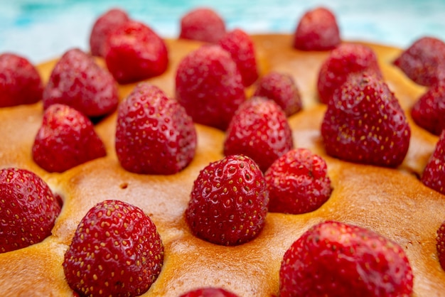 delicioso pastel de fresa de forma redonda con frutas en la parte superior en azul brillante