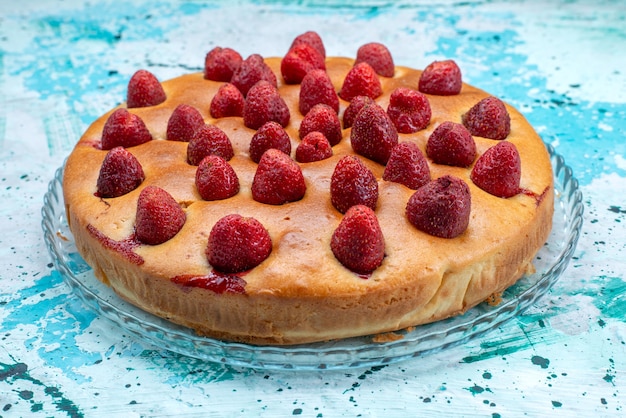 Delicioso pastel de fresa de forma redonda con frutas en la parte superior sobre azul brillante, masa de pastel de azúcar de galleta dulce