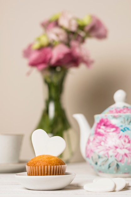 Delicioso pastel junto a las flores y tetera.