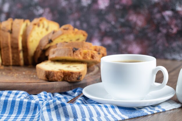 Delicioso pastel en un plato de madera con una taza de café a un lado