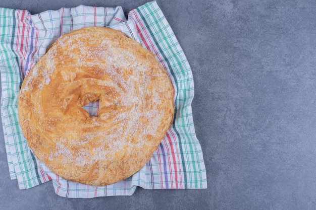 Foto gratuita un delicioso pastel redondo con azúcar en polvo sobre un mantel