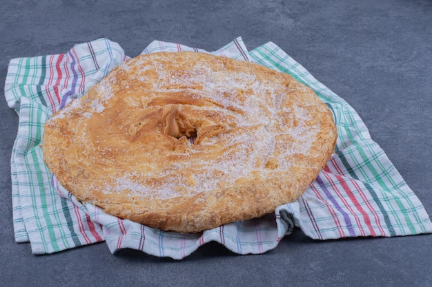 Foto gratuita un delicioso pastel redondo con azúcar en polvo sobre un mantel