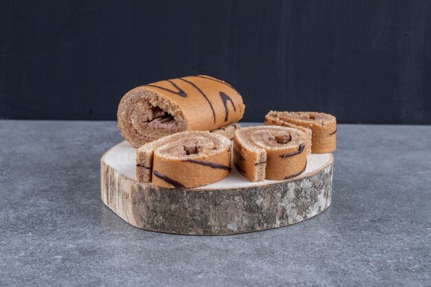 Delicioso pastel de rollo de chocolate sobre pieza de madera