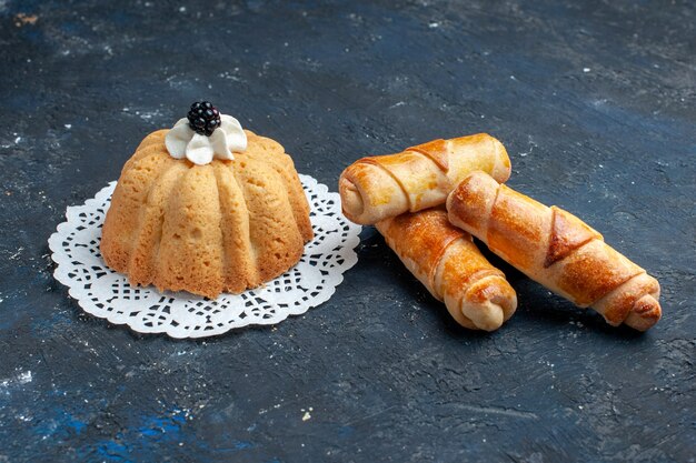 delicioso pastel simple con crema y moras junto con brazaletes en el escritorio oscuro