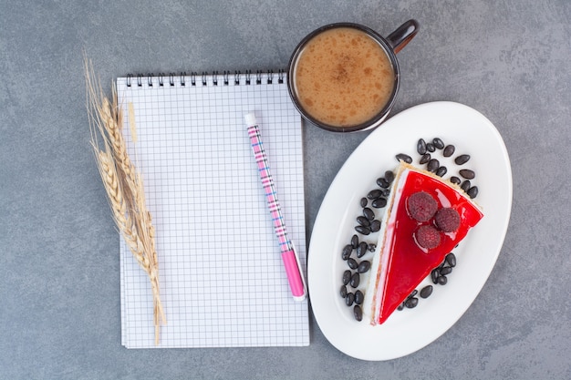 Un delicioso pedazo de pastel dulce con hoja de papel sobre la mesa gris.